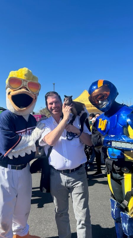 Allen and Sara posing with team mascots at a community event